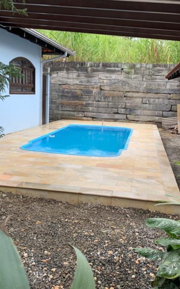 Piscina pequena com borda e piso de pedra clara
