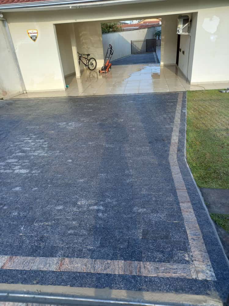 Piso de pedra escura na garagem com faixa clara de acabamento