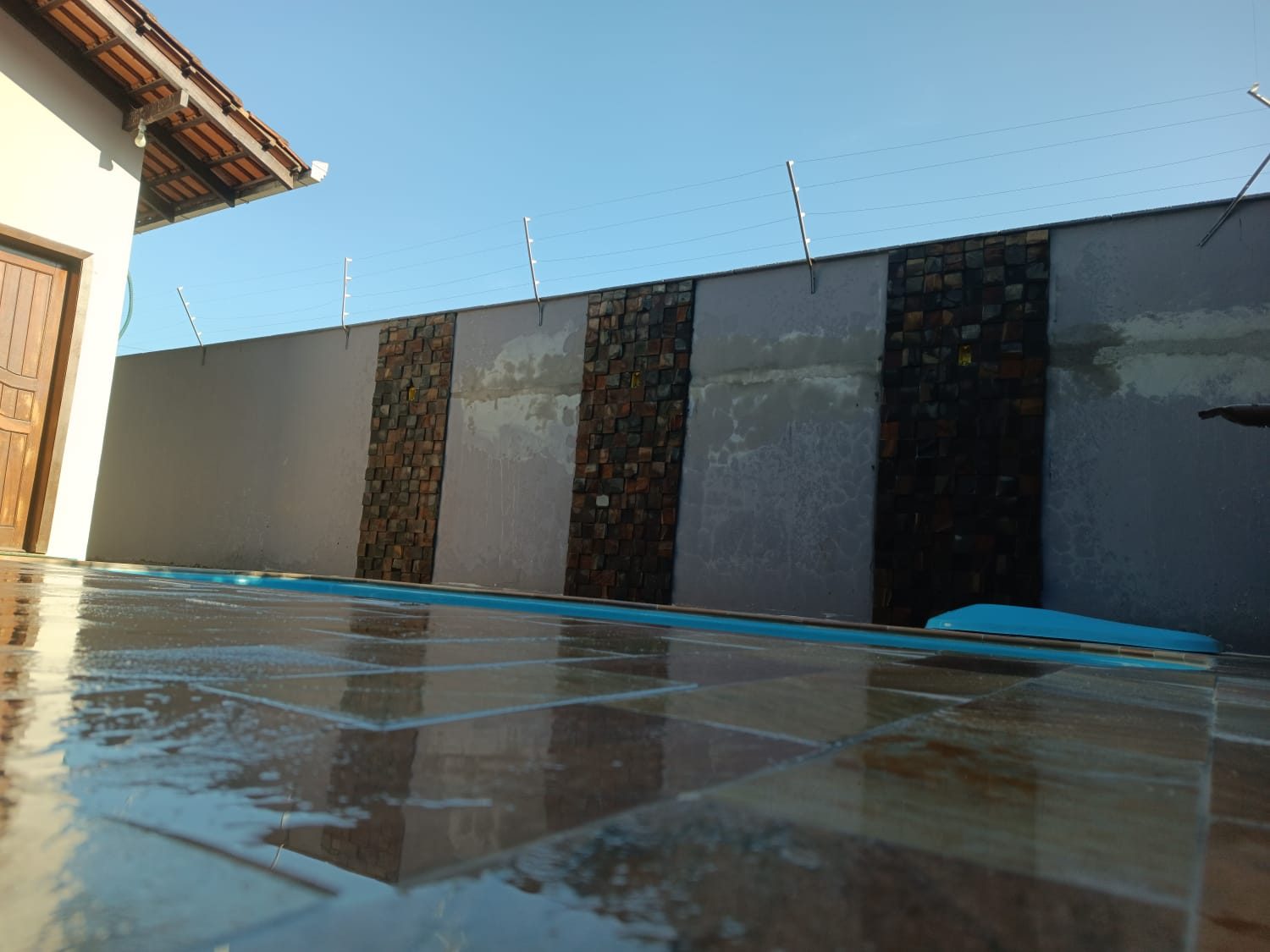 Muro revestido com faixas de filetes de pedra ao lado da piscina