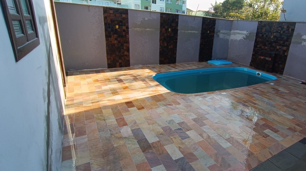 Piso de pedra em tons de amarelo e rosa em volta da piscina